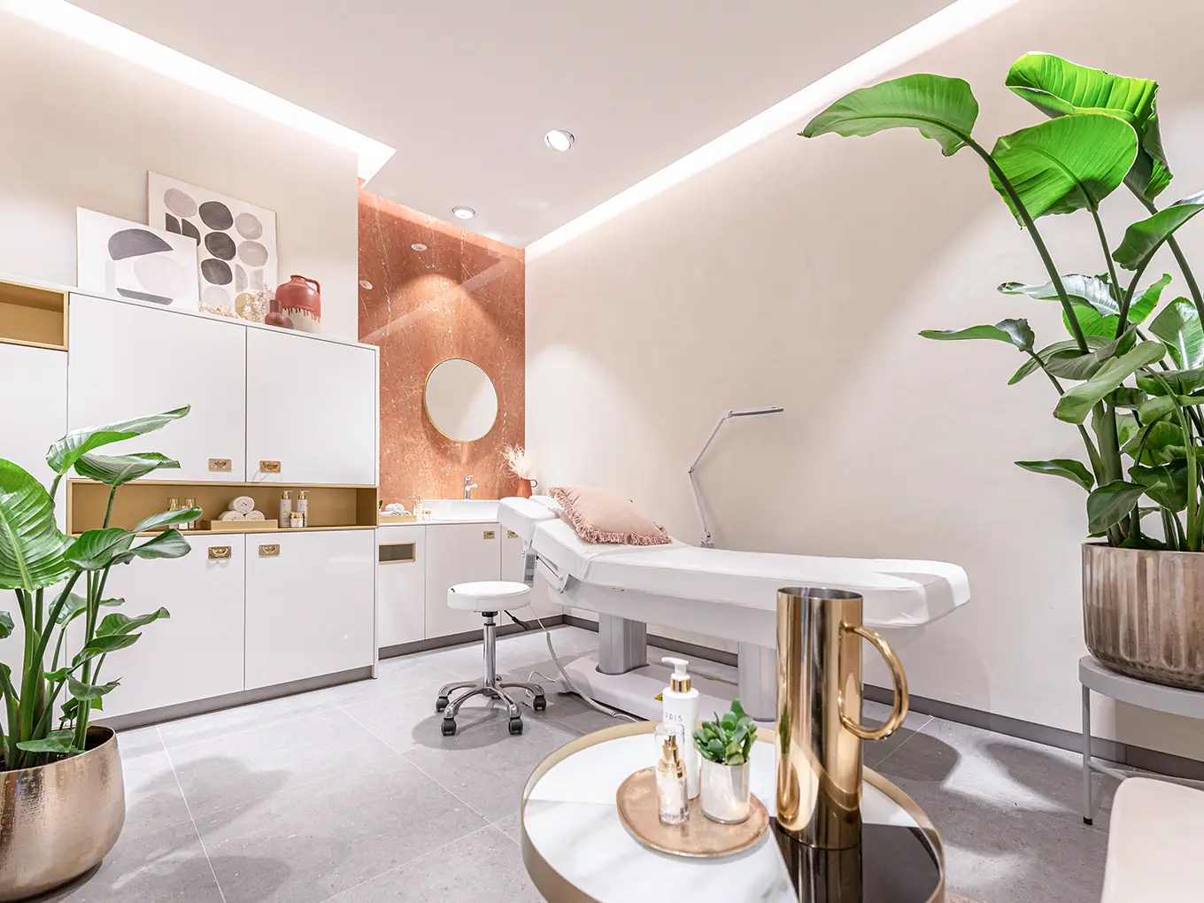 Stilvolles Behandlungszimmer bei Beauty by Leffers Modernes Behandlungszimmer mit Liege, weißen Schränken, Dekoration und großen Pflanzen in einem Schönheits- und Wellnessstudio.